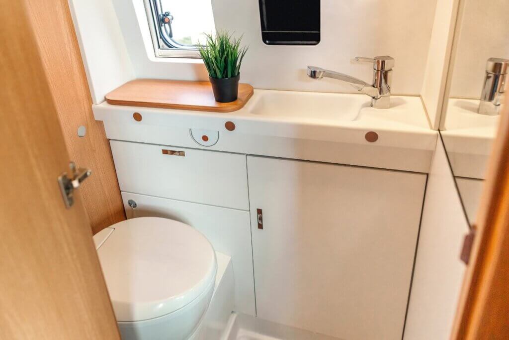 elaborate fixed toilet in a camper van bathroom with white cabinets.