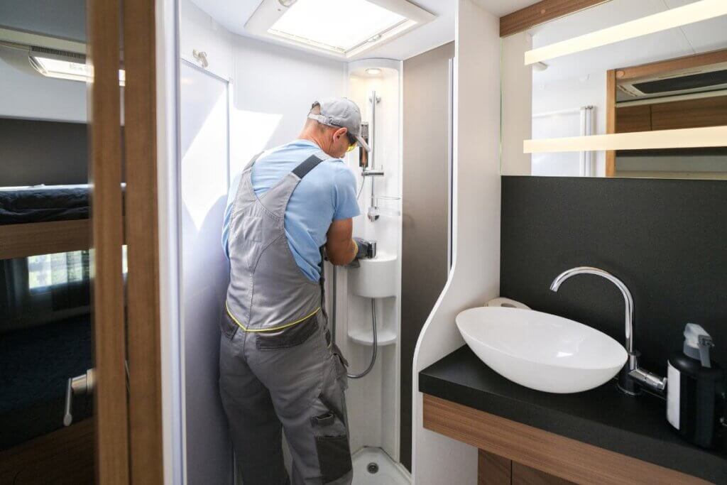 man fixing a camper van shower on the inside of the van