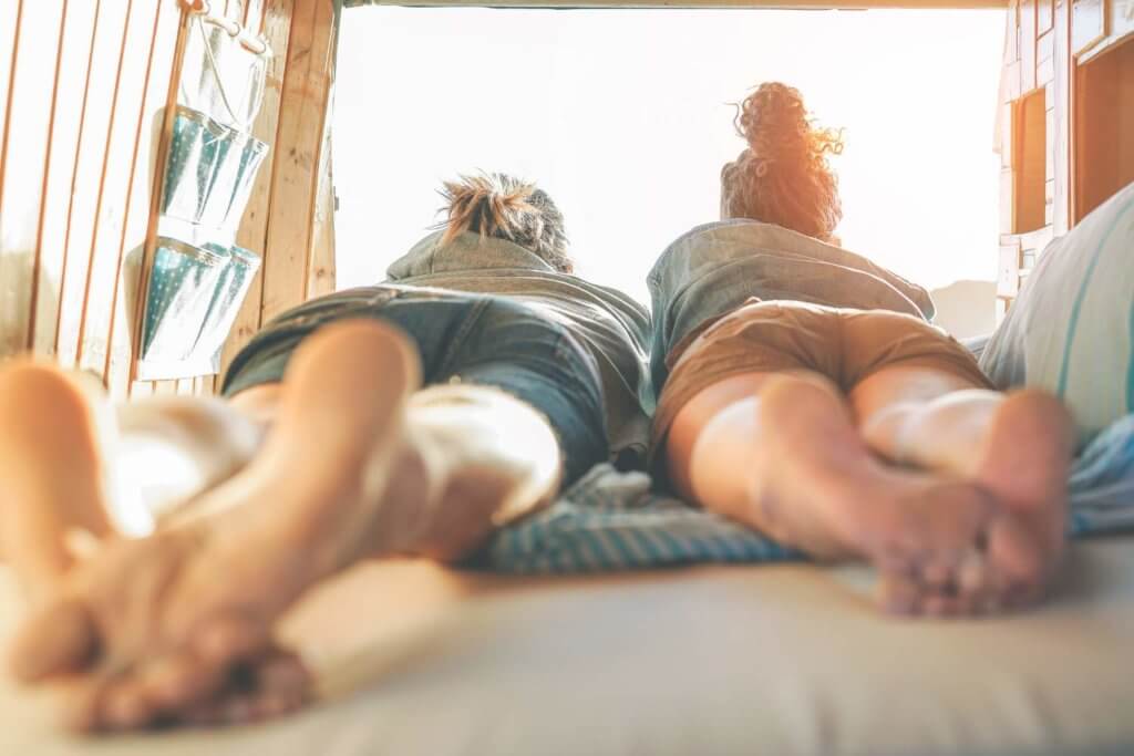 two people laying on a camper van bed option