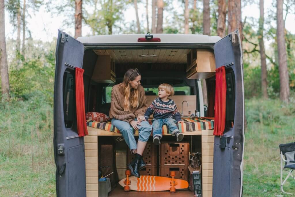 Mom and son sitting on a camper van bed in the back of a van