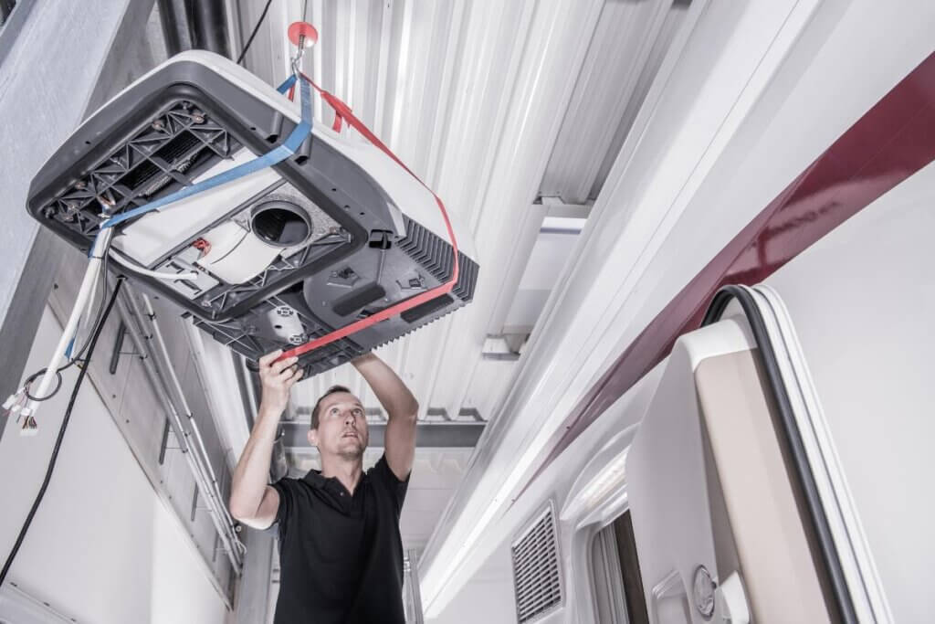 man installing a shore power camper van AC unit