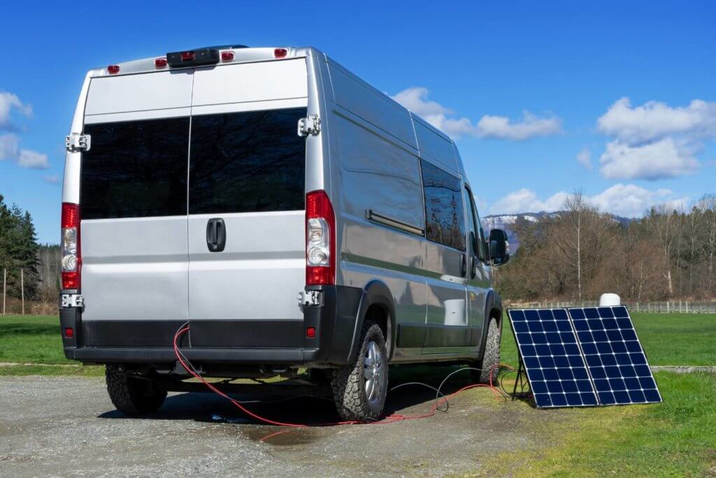 solar panel next to camper van charging a battery for a fridge