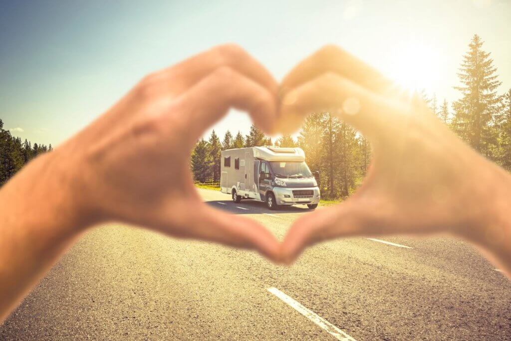 hands forming heart shape in front of a motorhome