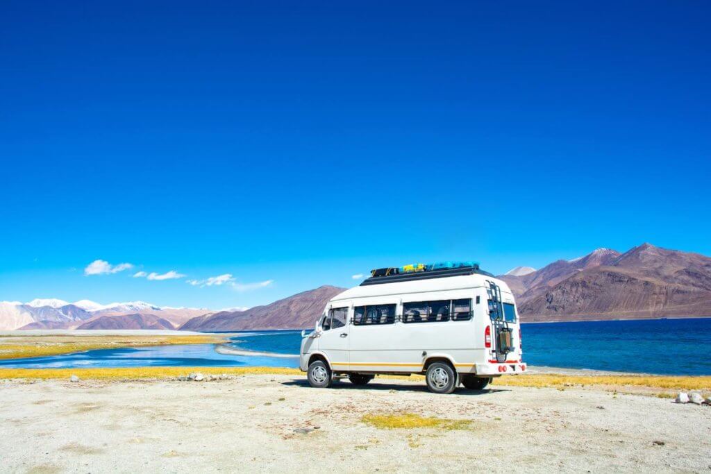 Camper van on a beach area in front of beautiful mountains. 
