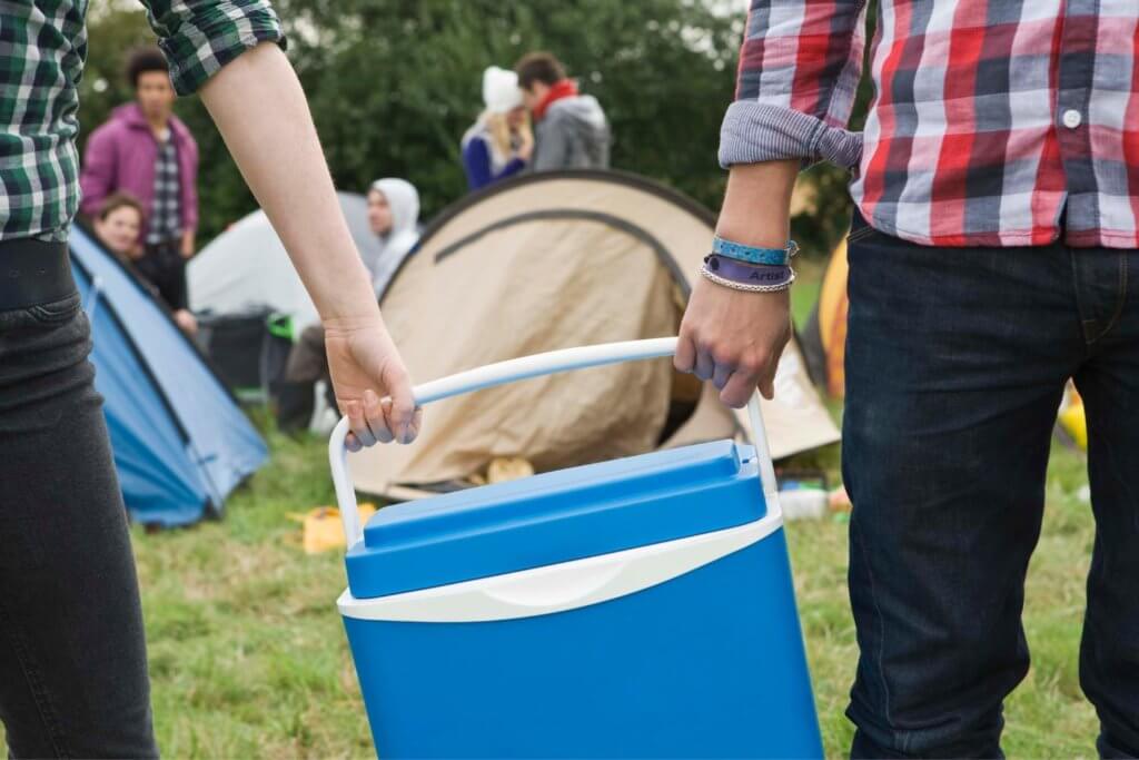 two people carrying a blue cooler
