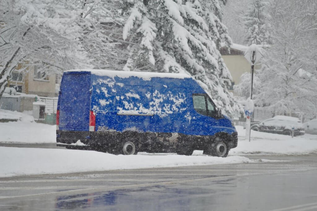 blue camper van on the side of the road in the snow