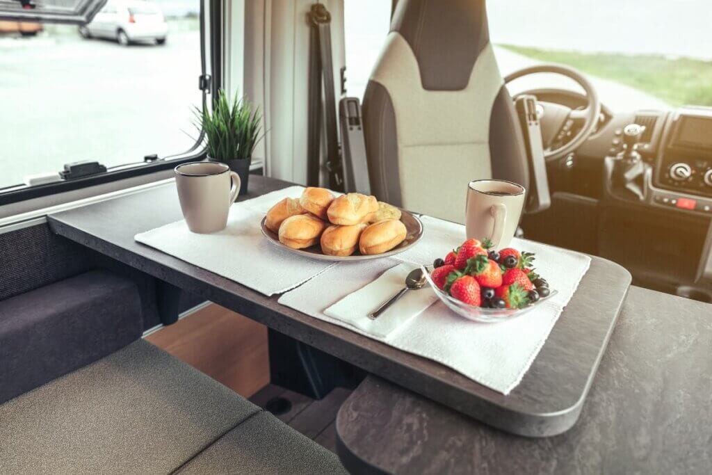 a table and chair set up in a camper van with food on table