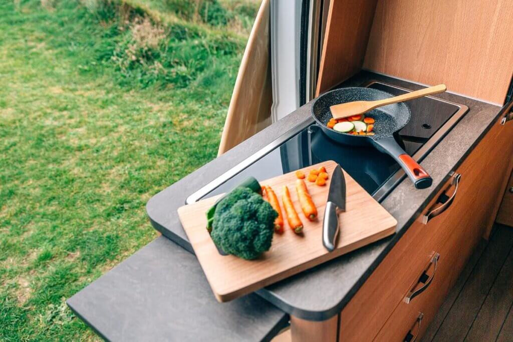 bamboo cutting board with veggies on top. in a camper van kitchen