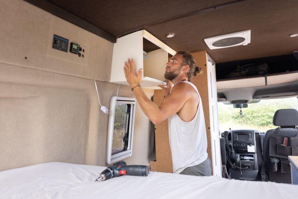 man installing camper van cabinets on ceiling