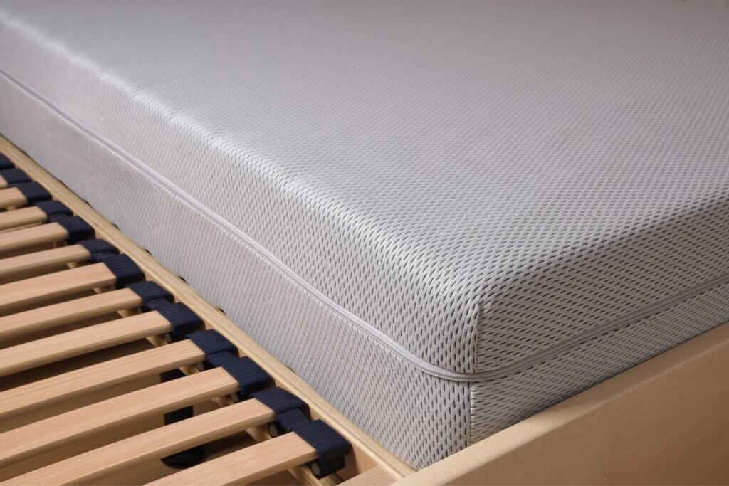 A thick mattress on top of a slat bed platform in a camper van