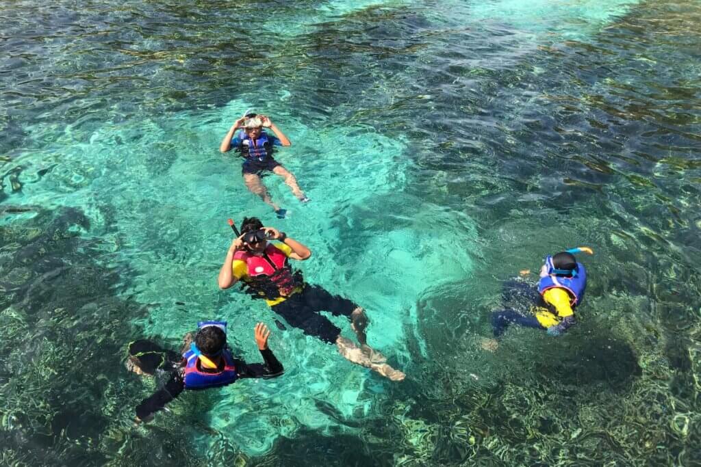 4 people with snorkel gear snorkeling in Oahu