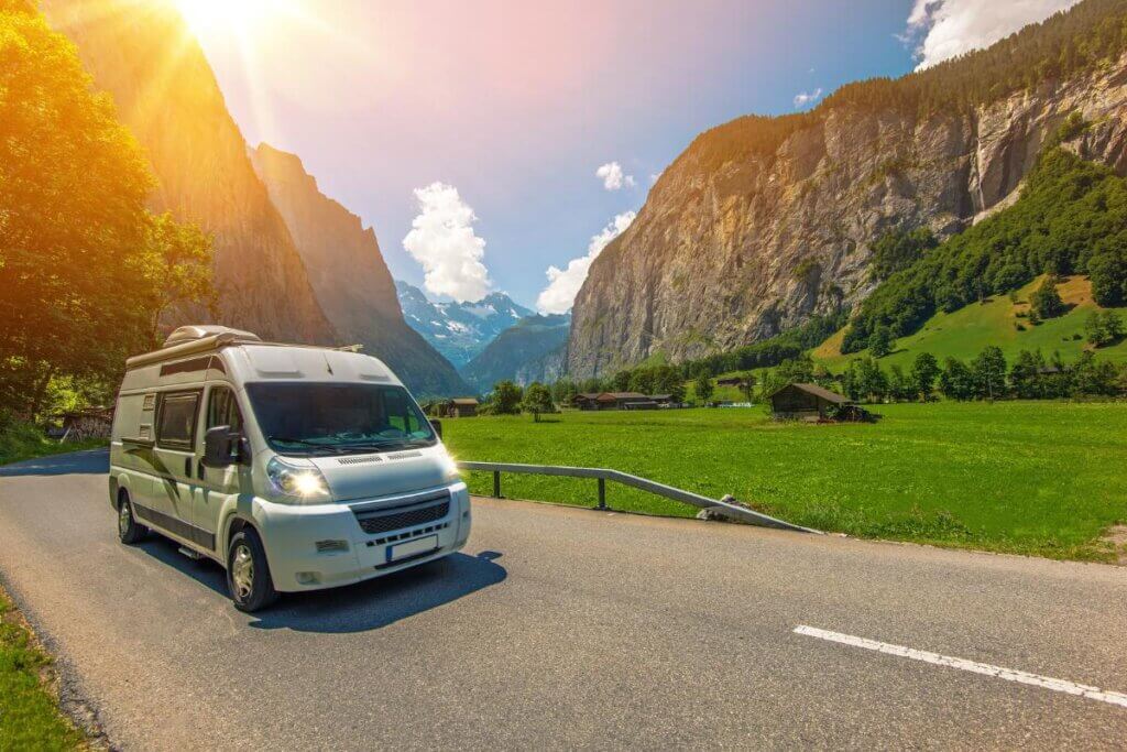 camper van cruising along a highway in the valley of several mountains