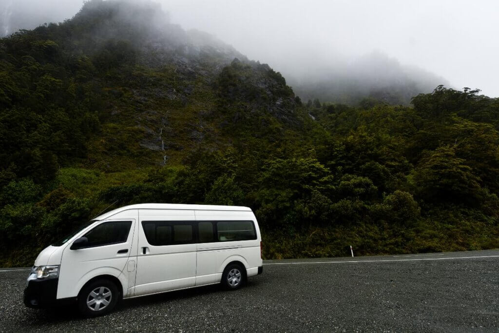 camper van on the road next to rainy mountains