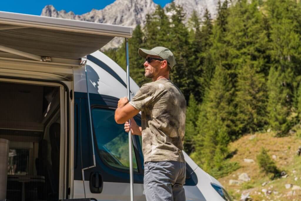 man putting up an awning to prepare for rain in a camper van